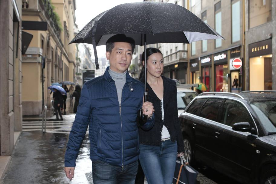 Il magnate thailandese Bee Taechaubol passeggia con la moglie sotto la pioggia nelle vie del centro di Milano (Ansa)